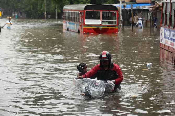 मुंबईत रविवारी झालेल्या मुसळधार पावसामुळे वेगवेगळ्या भागात पाणी साठले. त्याच पाण्यातून मार्ग काढताना एक दुचाकीस्वार. (छाया - प्रशांत नाडकर)