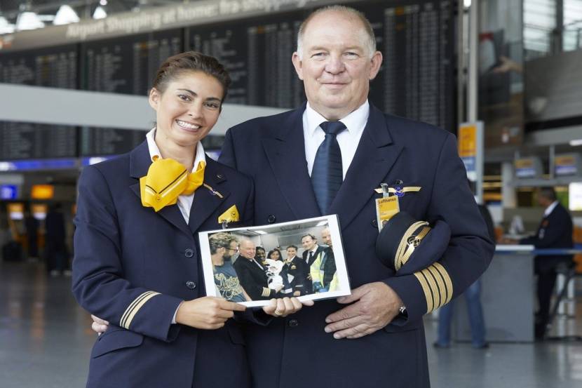 लुफ्तांसा एअरलाईनचे पायलट आणि क्रू मेंबर विमानात जन्मलेल्या बाळाचा फोटो दाखवताना.