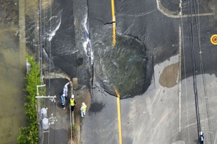 Water flows out from cracks in a road damaged by the earthquake