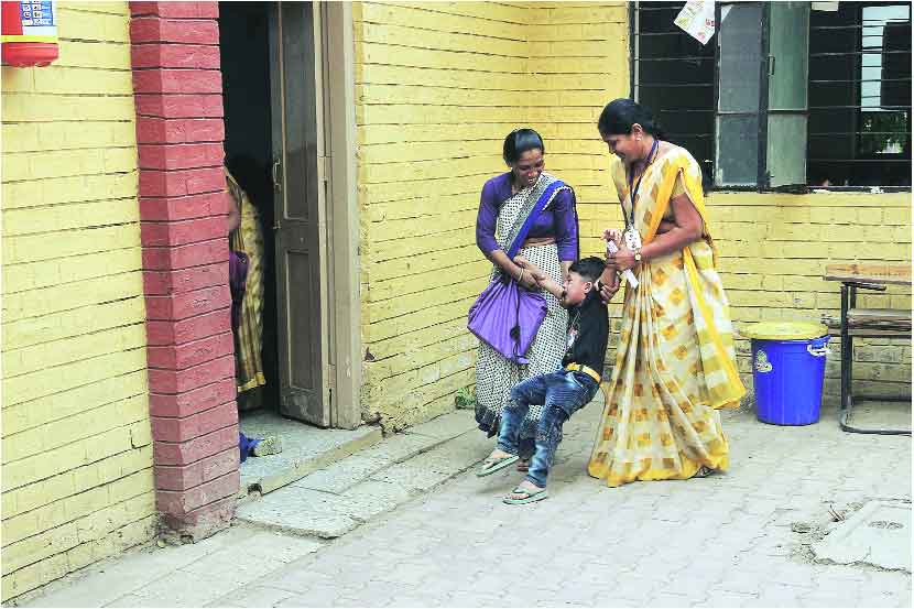 पालकांच्या ताब्यातून लहानगीला वर्गात नेण्यासाठी कर्मचाऱ्यांची कसरत (छाया- यतीश भानू)