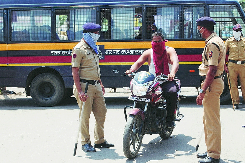 धुळे येथे शुक्रवारी राज्य राखीव पोलीस दलाच्या जवानांनी मास्क न घालता फिरणाऱ्या दुचाकीस्वारास अंगातील टी शर्ट काढून तोंडावर बांधायला लावला. (छाया- विजय चौधरी)