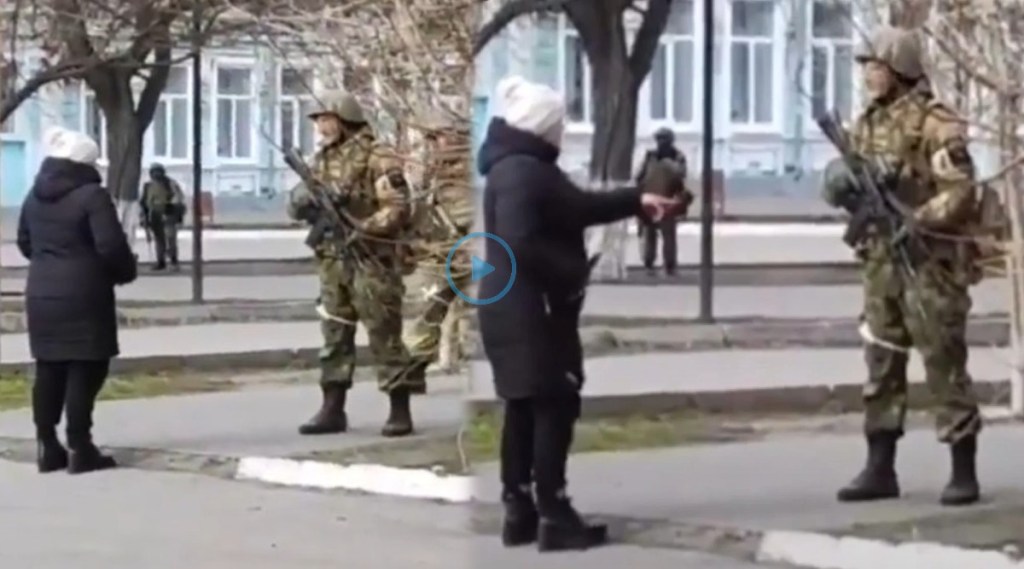 woman offers sunflower seeds to Russian soldier