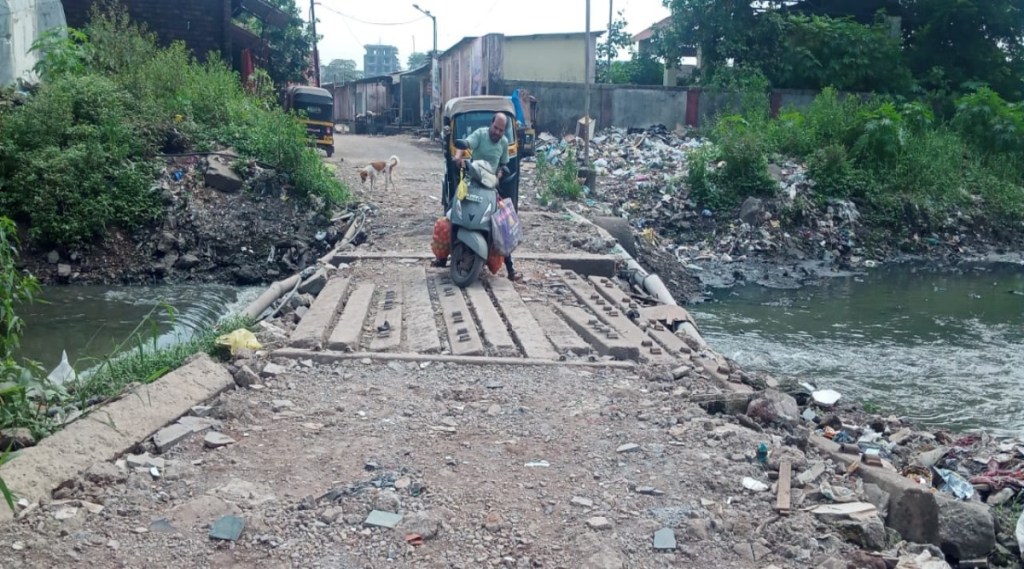 Passengers travel dangerously through the drain in Kopar East in Dombivli