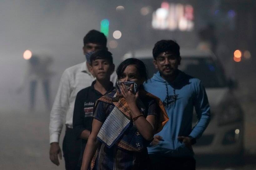 फटाक्यांच्या आतिषबाजीमुळे काही नागरिकांना श्वसनाचा त्रास सहन करावा लागला. यातून वाचण्यासाठी अहमदाबादेत तोंडावर पदर ठेवून चालताना महिला.(फोटो सौजन्य-एपी)