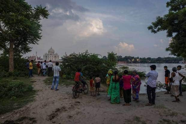 आग्रा येथे मुसळधार पावसामुळे यमुना नदी ओसंडून वाहत असल्याने लोक ऐतिहासिक ताजमहालासमोर पुराच्या पाण्याजवळ उभे आहेत. रॉयटर्स