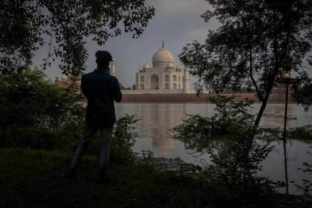आग्रा येथे मुसळधार पावसामुळे यमुना नदी ओसंडून वाहत असताना एक व्यक्ती ऐतिहासिक ताजमहालचे छायाचित्र घेत आहे. रॉयटर्स