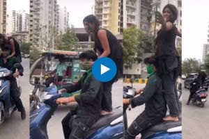 girl playing holi with boyfriend while standing on moving scooter