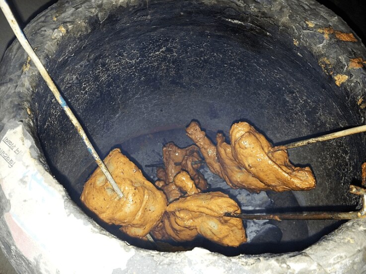 Tandoori chicken being prepared in a tandoor oven.
