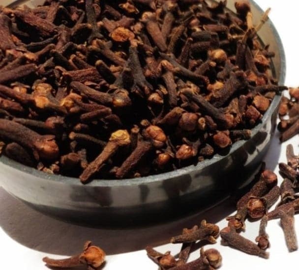 Spice cloves in bowl on white background selective focus.