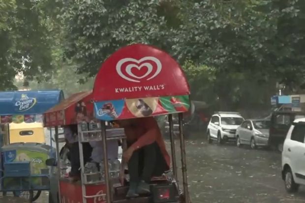 दिल्ली एनसीआरमध्ये मुसळधार पावसापासून स्वतःचे रक्षण करण्यासाठी फेरीवाले आणि रस्त्यावरील विक्रेते, आईस्क्रीम विक्रेते यांच्यासाठी कठीण परिस्थिती निर्माण झाली. (Photo: ANI)