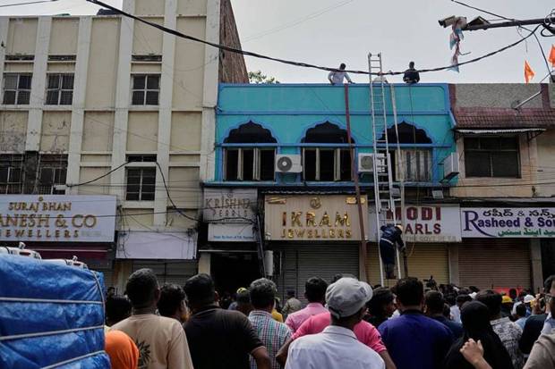 अग्निशमन दलाचे अधिकारी बचाव कार्य करत असताना लोक पाहत आहेत. (Photo source: AP)